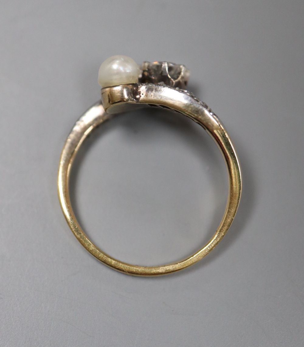 A yellow metal (stamped 18), diamond and cultured pearl set crossover ring, with diamond set shoulders, size M, gross 2.9 grams,
